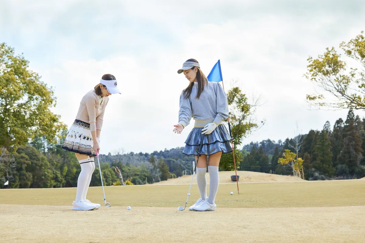 Two women golfers in coordinated hat styling on course